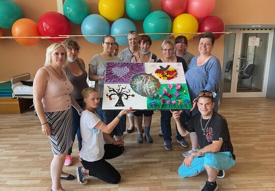 ein Gruppenfoto von einer Gruppe die ein Kunstwerk hochhalten mit verschiedenen Natur Motiven
