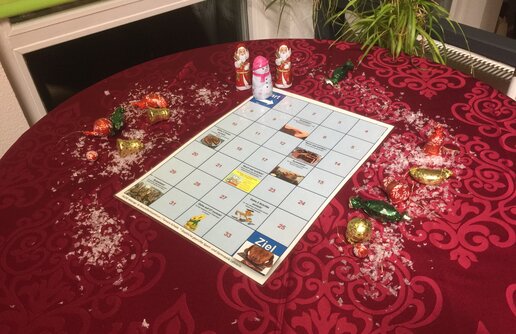 ein festlich gestalteter Tisch mit einem Spielbrett und 3 Schokoladen Figuren