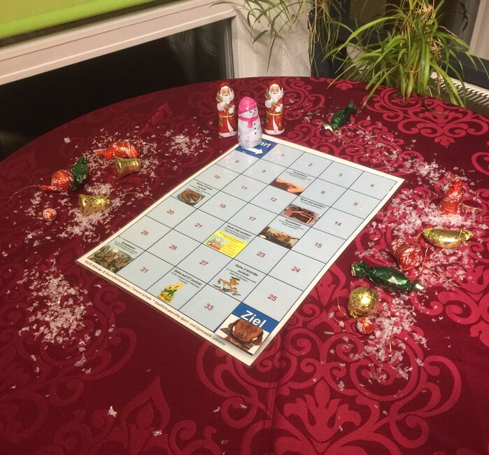 ein festlich gestalteter Tisch mit einem Spielbrett und 3 Schokoladen Figuren