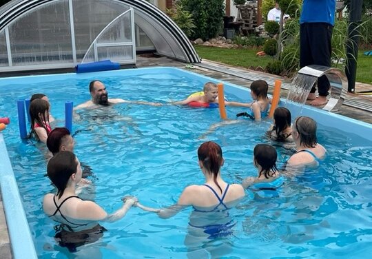 elf Personen im Wasser die sich an den Händen halten