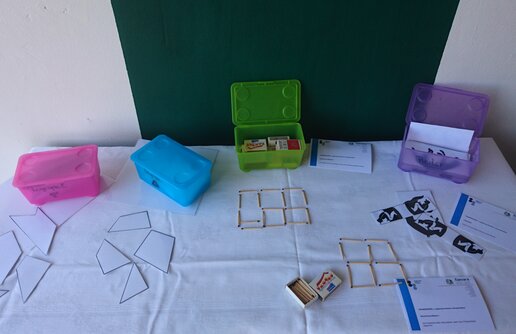 ein Tisch mit etwas größeren Papier Schnipseln und Streichhölzer die als Puzzle dienen.