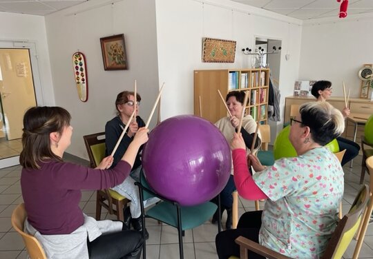 vier Damen trommeln auf einem Gymnastikball