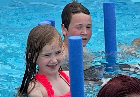 Aquasport Kinder Kinder mit blauen Schaumstangen im Pool