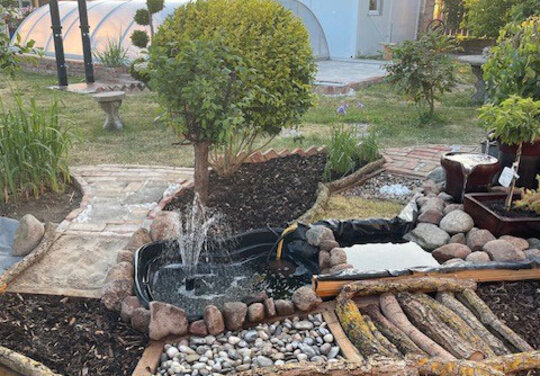 Der Barfußpfad aus einer anderen Perspektive, man erkennt einen Wintergarten im Hintergrund.