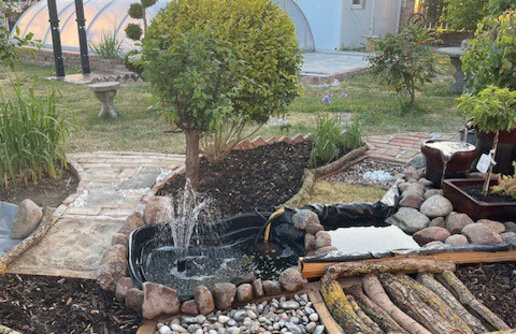 Der Barfußpfad aus einer anderen Perspektive, man erkennt einen Wintergarten im Hintergrund.