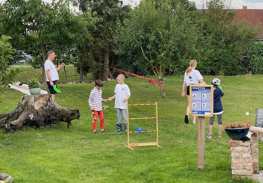 Kinder-Feriensport Kinder auf einer Wiese mit Parcourgegenständen