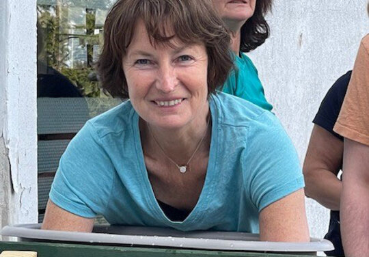 Eine Dame die mit den Armen in einem Wasserbecken liegt mit drei Beobachter/-innen