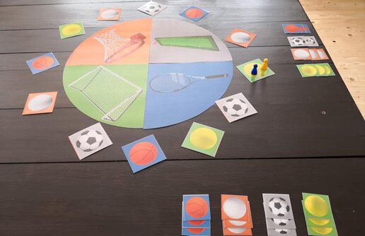 bunte Spielkarten mit Sportmotiven und zwei Spielfiguren
