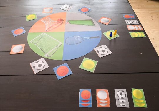 bunte Spielkarten mit Sportmotiven und zwei Spielfiguren