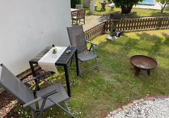 Ferienwohnung Garten Ferienwohnung Garten mit zwei Stühlen und Tisch auf einer Wiese