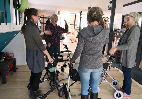 fünf Damen mit Rollatoren stehen um einen Hula Hoop Reifen